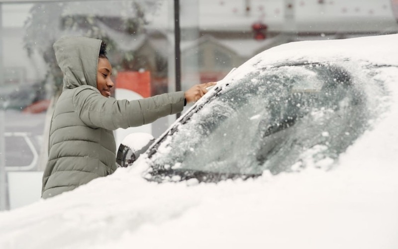 Texas cold front causes heavy snow as a person clears ice from a car windshield