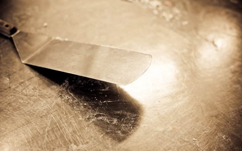 How to clean a Blackstone flat top grill using a scraper to remove food residue