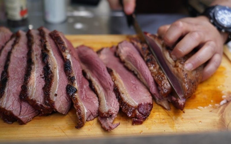 Cutting cooked brisket into slices after resting for a tender texture